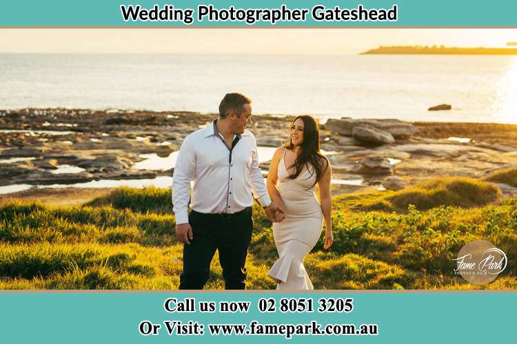 Photo of the Groom and the Bride walking near the shore as they look at each other Gateshead