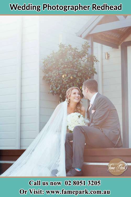 Photo of the Bride and the Groom looking each other while sitting at the staircase Redhead NSW 2290